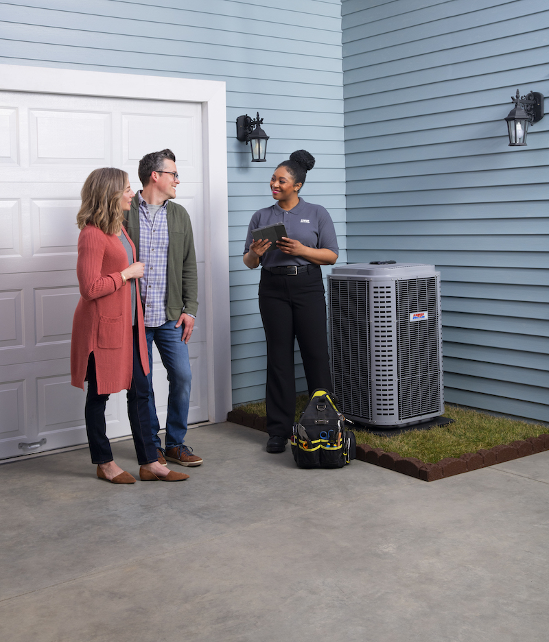 Happy couple talking to female service technician by new AC unit